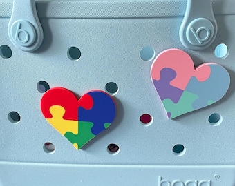 May include: A light blue tote bag with two heart-shaped jigsaw pieces attached. The jigsaw pieces are made of different colours, including red, blue, yellow, green, pink, purple, and light blue.