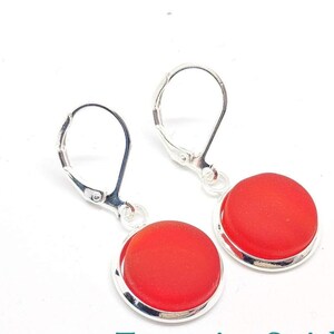 May include: A pair of silver earrings with red glass cabochons. The earrings have lever back closures.