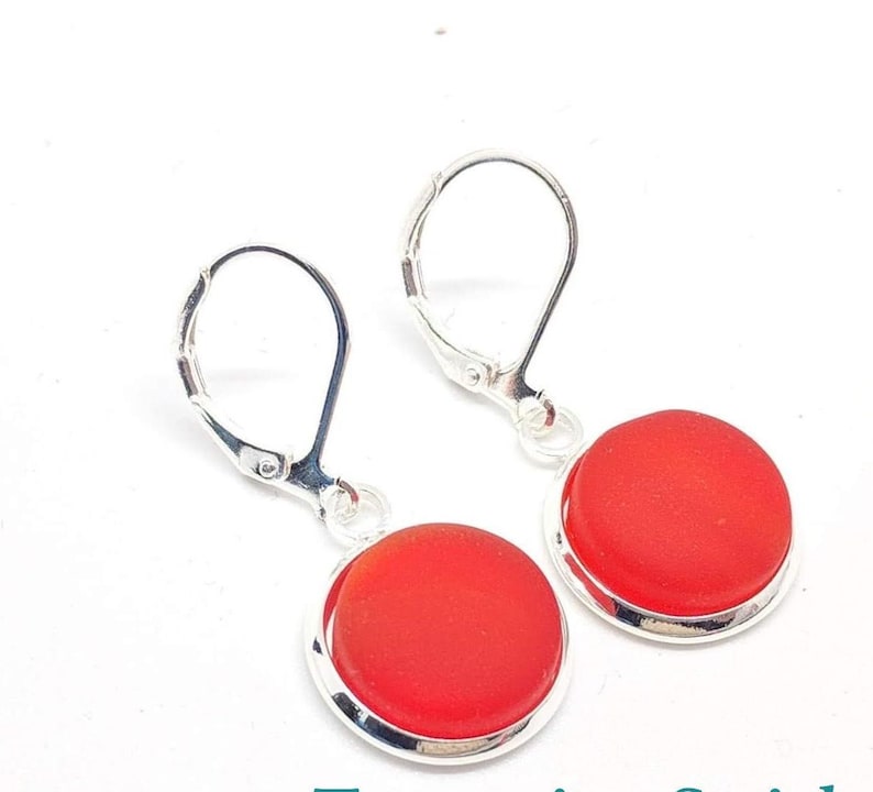 May include: A pair of silver earrings with red glass cabochons. The earrings have lever back closures.