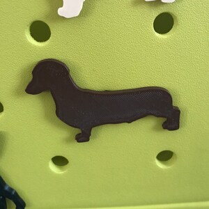 May include: A brown dachshund silhouette cutout on a green background.