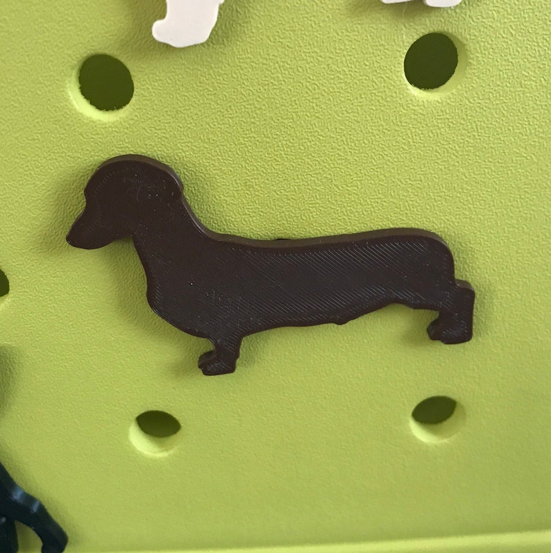 May include: A brown dachshund silhouette cutout on a green background.