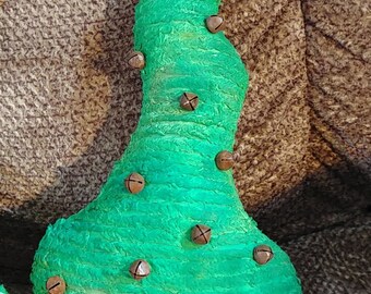 May include: A handcrafted, green Christmas tree decoration with a textured surface. The tree is adorned with small, brown bells and topped with a star. The base is a dark brown color.