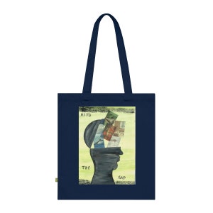 May include: Navy blue tote bag featuring an artistic design. The design includes a silhouette of a head with an open top, revealing a collage of images. The words "MIND THE GAP" are printed on the bag.