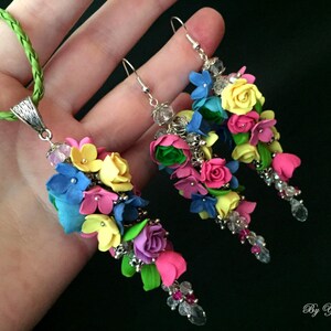 Peut inclure: Un ensemble de boucles d'oreilles et d'un collier assorti de fleurs color&eacute;es. Les boucles d'oreilles et le collier pr&eacute;sentent une cascade de fleurs en p&acirc;te polym&egrave;re rose, jaune, bleue et verte avec des accents de cristal.