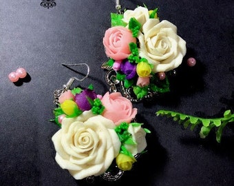 Peut inclure: Une paire de boucles d'oreilles florales avec des fleurs blanches, roses et violettes. Les boucles d'oreilles sont en pâte polymère et ont des attaches en métal argenté.