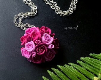 Peut inclure: Un collier en chaîne argent avec un pendentif en forme de bouquet de roses en pâte polymère rose et violette.