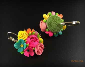 Op de afbeelding: Een paar kleurrijke bloemen oorbellen met een groene achterkant. De oorbellen zijn gemaakt van polymer clay en hebben een zilveren haak.