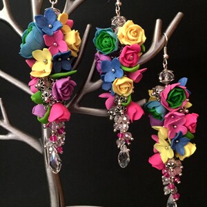 Peut inclure: Un ensemble de boucles d'oreilles et d'un collier assorti de fleurs color&eacute;es. Les boucles d'oreilles et le collier pr&eacute;sentent des fleurs roses, jaunes, bleues, vertes et blanches avec des accents de cristal.