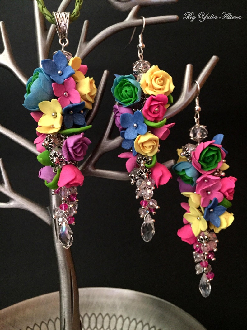 Peut inclure: Un ensemble de boucles d'oreilles et d'un collier assorti de fleurs color&eacute;es. Les boucles d'oreilles et le collier pr&eacute;sentent des fleurs roses, jaunes, bleues, vertes et blanches avec des accents de cristal.