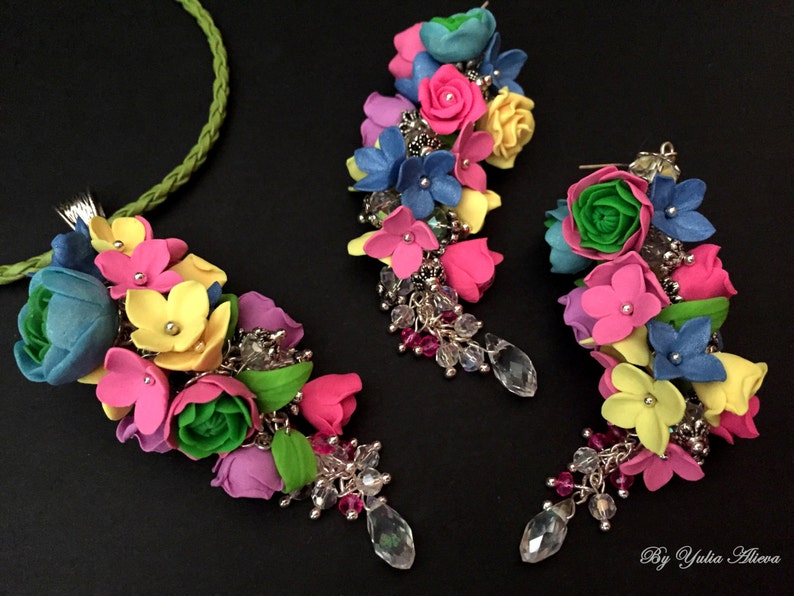 Peut inclure: Un collier et des boucles d'oreilles assortis de fleurs color&eacute;es, avec des fleurs roses, jaunes, bleues et vertes. Le collier a une cha&icirc;ne argent&eacute;e et les boucles d'oreilles ont des crochets argent&eacute;s.