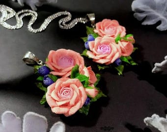 Peut inclure: Deux pendentifs délicats en forme de rose rose avec des baies bleues et des feuilles vertes. Les pendentifs sont attachés à des chaînes argentées.