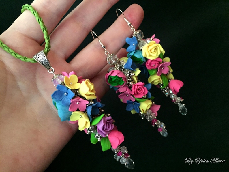 Peut inclure: Un ensemble de boucles d'oreilles et d'un collier assorti de fleurs color&eacute;es. Les boucles d'oreilles et le collier pr&eacute;sentent une cascade de fleurs en p&acirc;te polym&egrave;re rose, jaune, bleue et verte avec des accents de cristal.