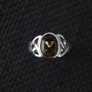 May include: A silver ring with a brown oval gemstone set in a Celtic knot design.