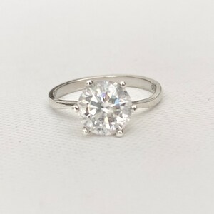 May include: A silver ring with a large, clear, round gemstone.