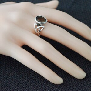 May include: A silver ring with a brown gemstone set in a Celtic knot design.