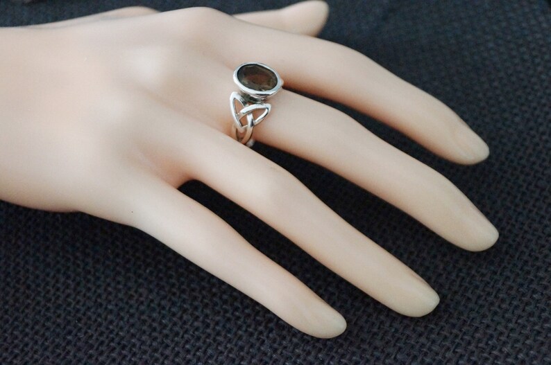 May include: A silver ring with a brown gemstone set in a Celtic knot design.