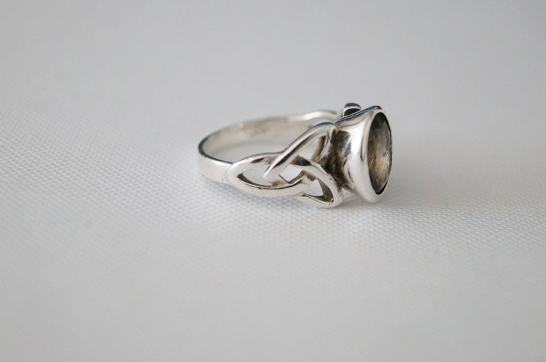 May include: A silver ring with a Celtic knot design and a clear gemstone.