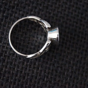 May include: A silver ring with a round, faceted gemstone. The ring has a delicate, intricate design.