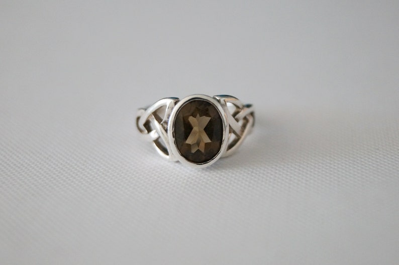 May include: A silver ring with a brown oval gemstone set in a Celtic knot design.