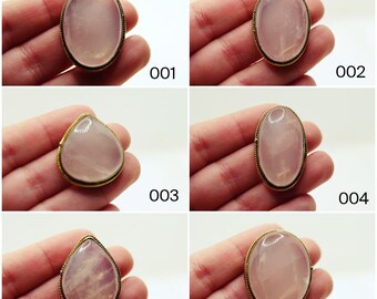 May include: Six close-up images of pink oval-shaped stones set in gold-toned metal. The stones are smooth and translucent, with a slight shimmer.
