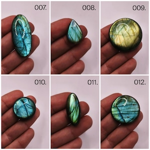 May include: A collection of six polished labradorite gemstones in various shapes. The stones display iridescent blue, green, and gold flashes. Each stone is held in a hand, with the numbers 007 through 012 visible in the image.