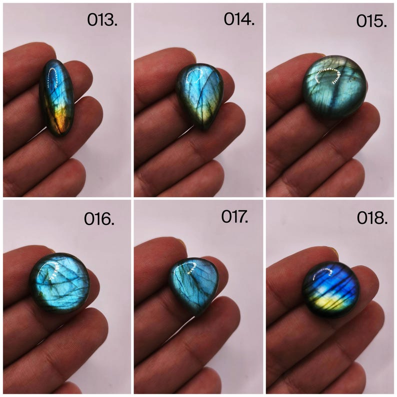 May include: Six polished labradorite gemstones in various shapes: oval, teardrop, and round. Each stone displays a vibrant play of color, with blues, greens, and yellows shimmering across their surfaces. The gemstones are held in a hand, showcasing their natural beauty.