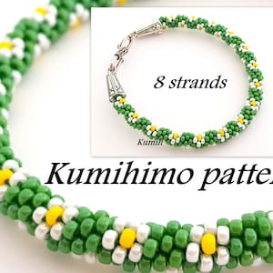 May include: Green and white beaded bracelet with yellow flower accents. The bracelet is made with 8 strands of beads and has a silver clasp. The bracelet is labelled "Kumihimo pattern".