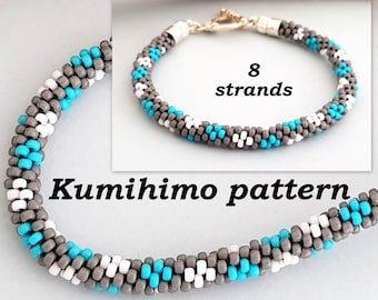 May include: A gray, white, and turquoise beaded bracelet made with the kumihimo technique. The bracelet is made with 8 strands of beads and has a silver clasp. The text "Kumihimo pattern" is written below the bracelet.