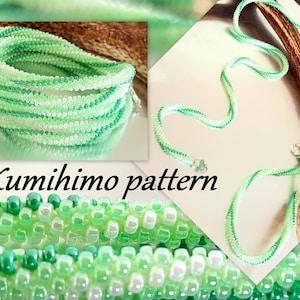 Puede incluir: Un collar kumihimo verde y blanco con un degradado de color. El collar está hecho de pequeñas cuentas y se muestra en primer plano. El texto "Kumihimo pattern" es visible en la imagen.