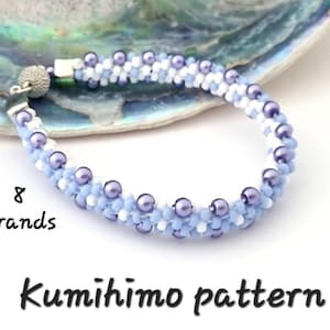 May include: A close-up of a light blue, white and purple beaded bracelet made using the kumihimo braiding technique. The bracelet is made with 8 strands of beads and has a silver clasp. The text "8 strands" and "Kumihimo pattern" is visible in the image.