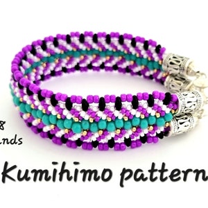 Puede incluir: Un brazalete de cuentas de color morado, blanco, negro y turquesa con cierres de plata. El brazalete está hecho con 8 hilos de cuentas y es un patrón Kumihimo.