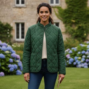 Könnte beinhalten: Eine gesteppte, dunkelgrüne Jacke mit rundem Kragen und zwei Vordertaschen. Die Jacke hat ein Rautenmuster und ist zugeknöpft. Die Person trägt eine blaue Jeans und einen cremefarbenen Pullover darunter.