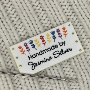 Peut inclure: Étiquette en tissu blanc avec des fleurs brodées colorées et le texte "Handmade by Jasmine Silver".