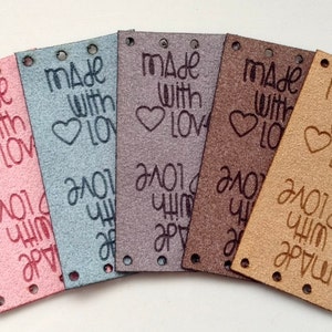 May include: Five leather tags in different colours, each with the text "made with love" and a heart design. The tags have holes punched along the top edge.