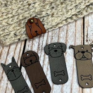 May include: Five different dog-shaped leather patches with a bone design. The patches are brown, grey, and tan.