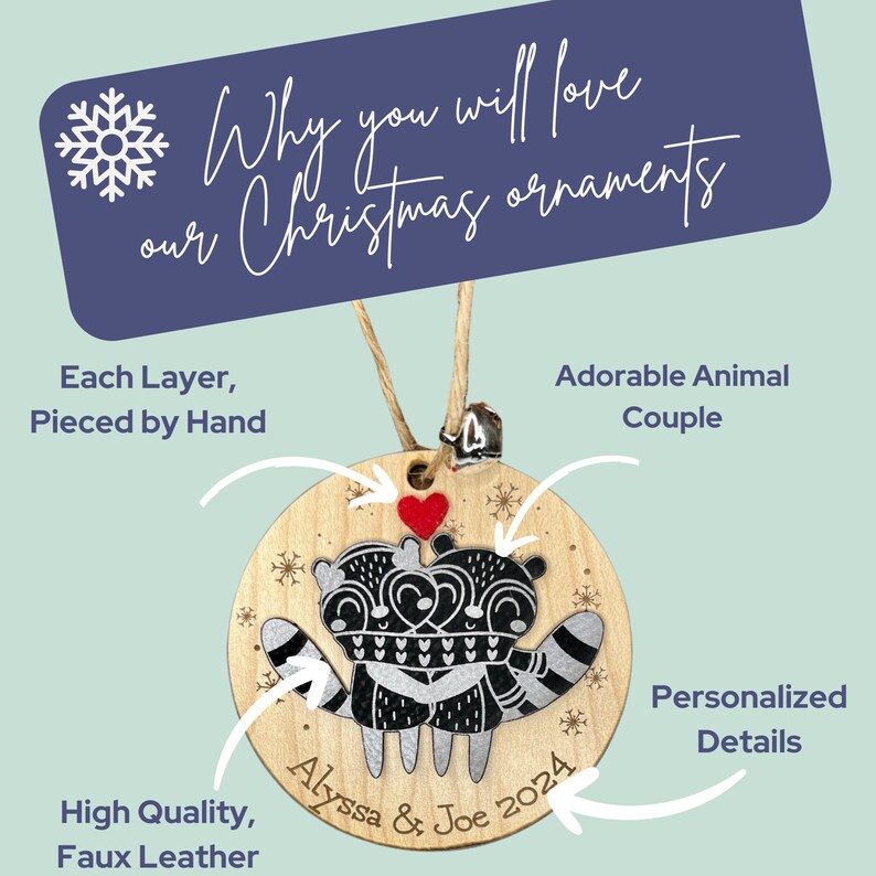 May include: A round wooden Christmas bauble featuring a pair of raccoons holding a heart. The bauble is personalised with the names "Alyssa & Joe" and the year "2024".