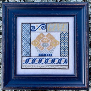 May include: A framed cross-stitch embroidery with a blue and yellow floral design and the word "GIVE" in the center.