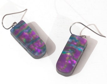 May include: A pair of iridescent purple and green dangle earrings with silver hooks. The earrings are made of resin and have a unique, marbled pattern.