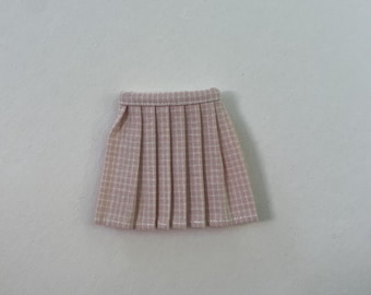 Peut inclure: Une jupe plissée rose clair avec un motif à carreaux subtil. La jupe a une ceinture structurée et des plis réguliers, créant un look classique. Le tissu semble être un matériau léger, adapté aux températures plus chaudes. La jupe mesure environ 25 cm de long.