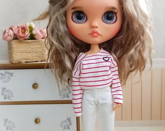 May include: A doll with long, wavy blonde hair wearing a red and white striped long-sleeved shirt with a small heart on the front and white pants.