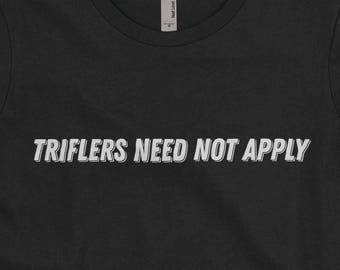 May include: Black t-shirt with the text "Triflers Need Not Apply" in white lettering.