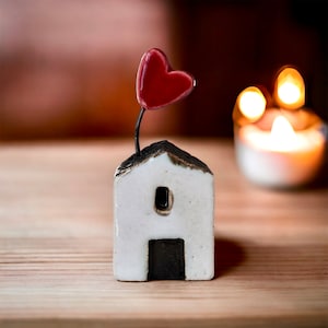 A white miniature house with a heart. A decorative ceramic house.