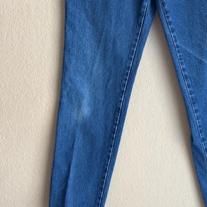 Op de afbeelding: Close-up van een blauwe spijkerbroek. De jeans heeft een medium wassing met een rechte pijp. Er is een lichte verkleuring op het linkerbeen. De jeans is gemaakt van een duurzame denim stof.