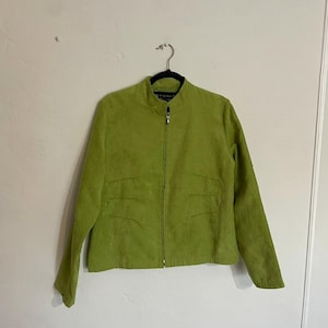 May include: A lime green suede jacket with a full-length zipper and a stand-up collar. The jacket has two front pockets and long sleeves. The jacket is hanging on a black hanger against a white wall.