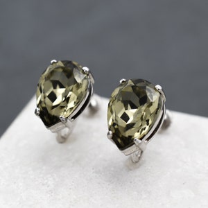 May include: A pair of silver earrings with pear-shaped green gemstones.