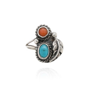 Op de afbeelding: Een zilveren ring met een turquoise en koraal steendesign. De ring heeft een gedetailleerd, ingewikkeld ontwerp.