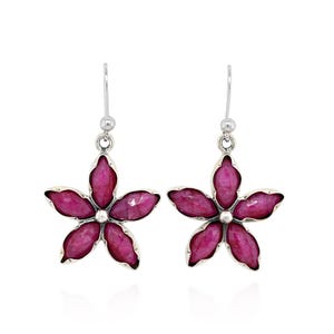 May include: A pair of silver flower earrings. Each earring features a five-petal flower design with a bright pink gemstone center and petals. The earrings have a simple hook closure.