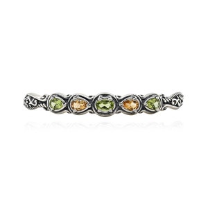 May include: A silver bracelet with a delicate design featuring green and orange gemstones.