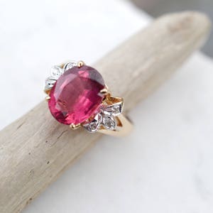 May include: A gold ring with a large oval pink gemstone surrounded by smaller white gemstones.