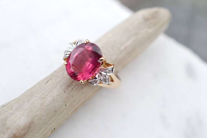 May include: A gold ring with a large oval pink gemstone surrounded by smaller white gemstones.